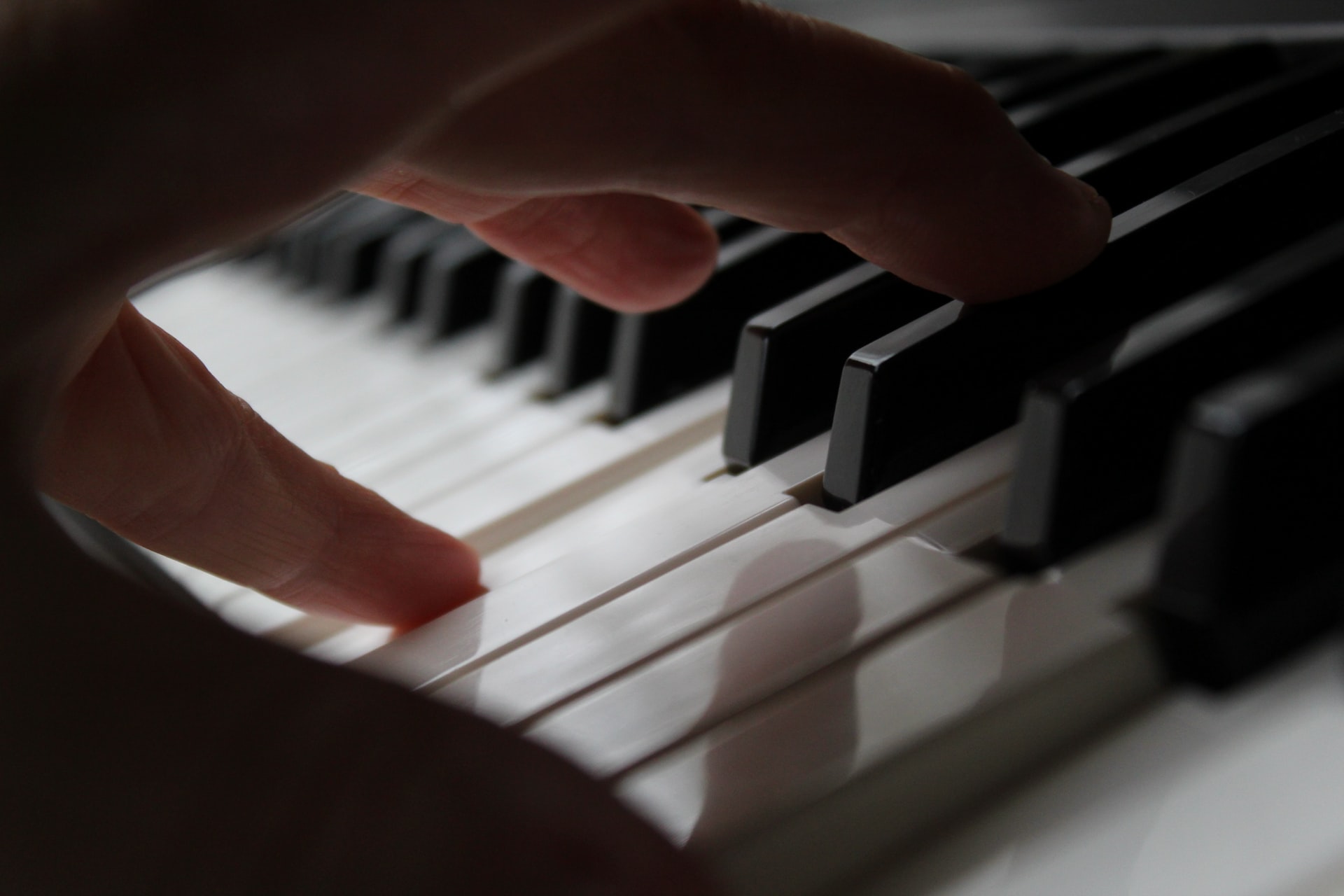 Persons hand on piano keys, composer.